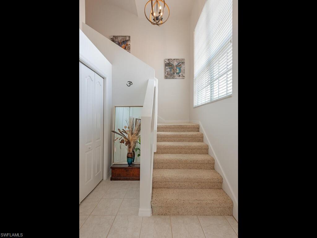 Staircase with tile patterned flooring, hanging lights, and a high ceiling