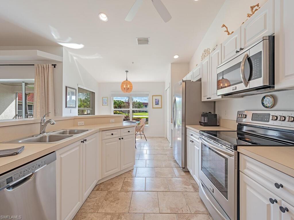 Kitchen with stainless steel appliances, light countertops, and white cabinetry