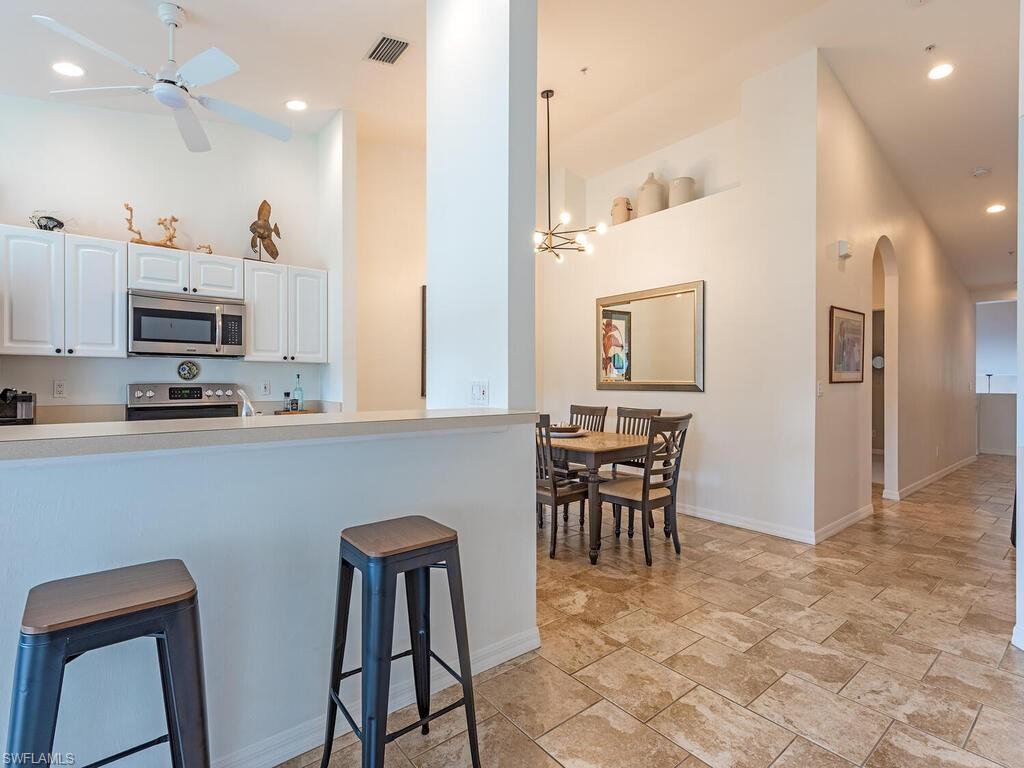 Kitchen featuring white cabinets, a ceiling fan, light countertops, stainless steel appliances, and arched walkways