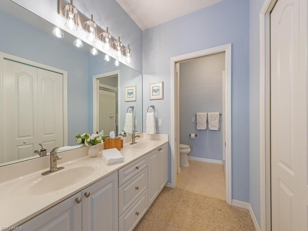 Full bathroom with double vanity and light carpet