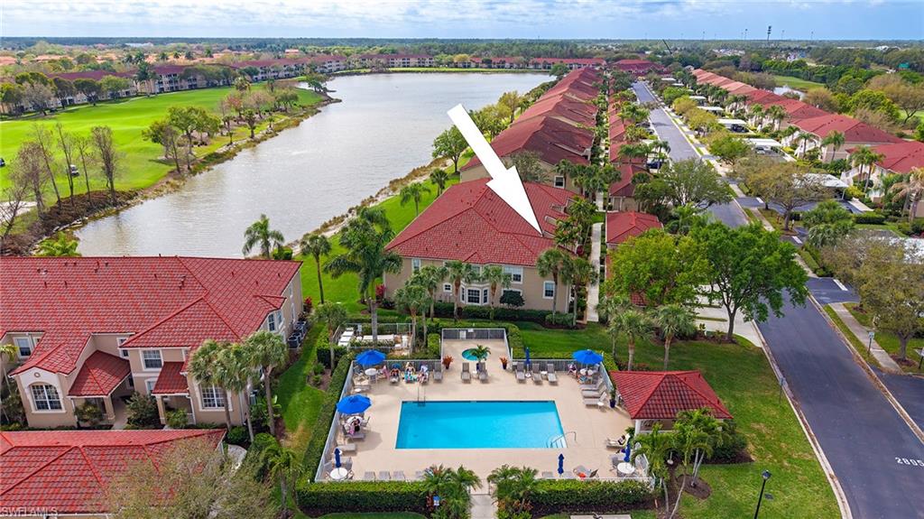 Aerial view of residential area featuring a nearby body of water and a pool area
