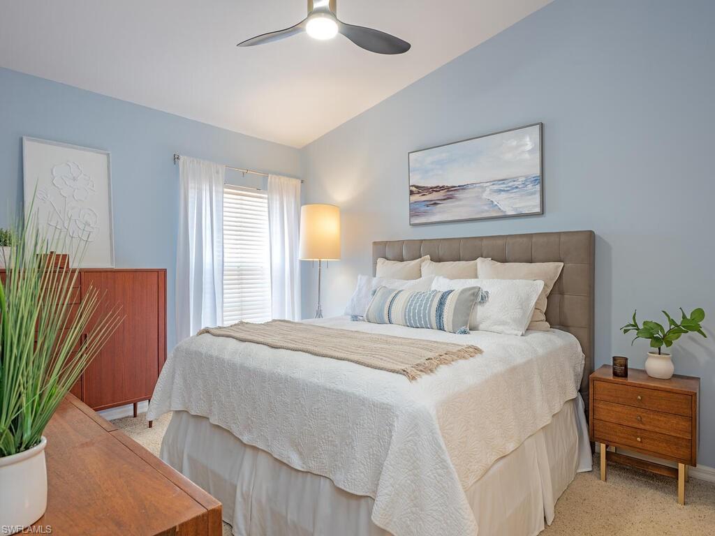 Bedroom featuring vaulted ceiling, a ceiling fan, and light carpet