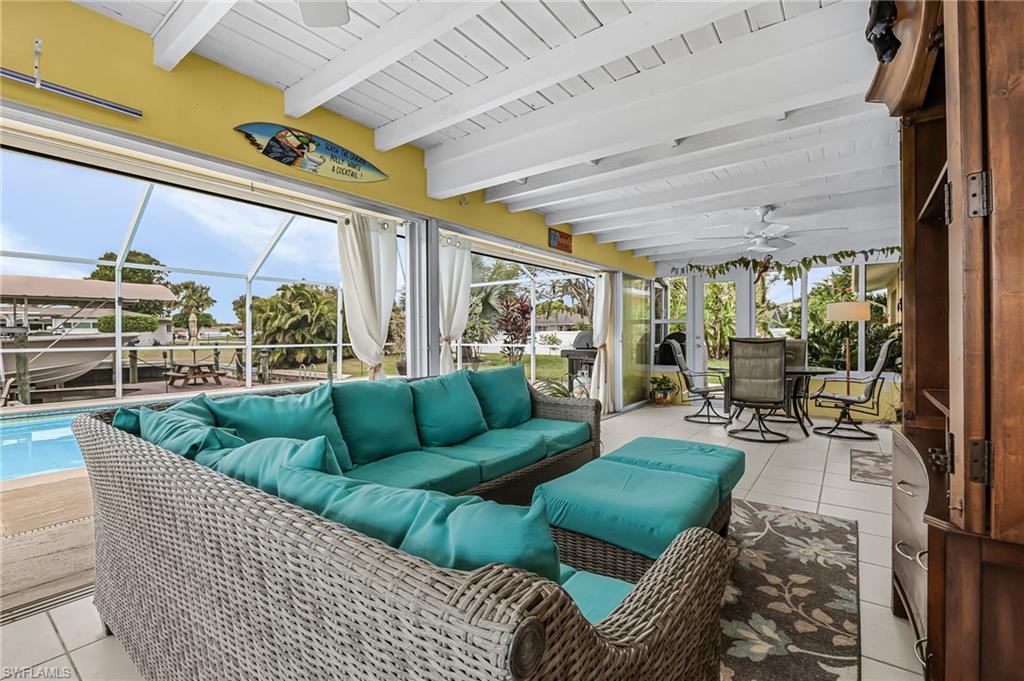Sunroom with a ceiling fan, outdoor lounge area, beamed ceiling, and a patio