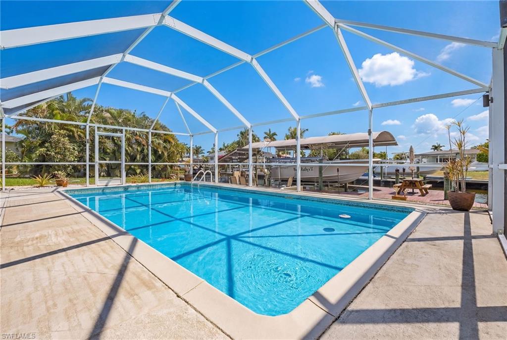 Swimming pool with boat lift, a patio, glass enclosure, and a sunroom