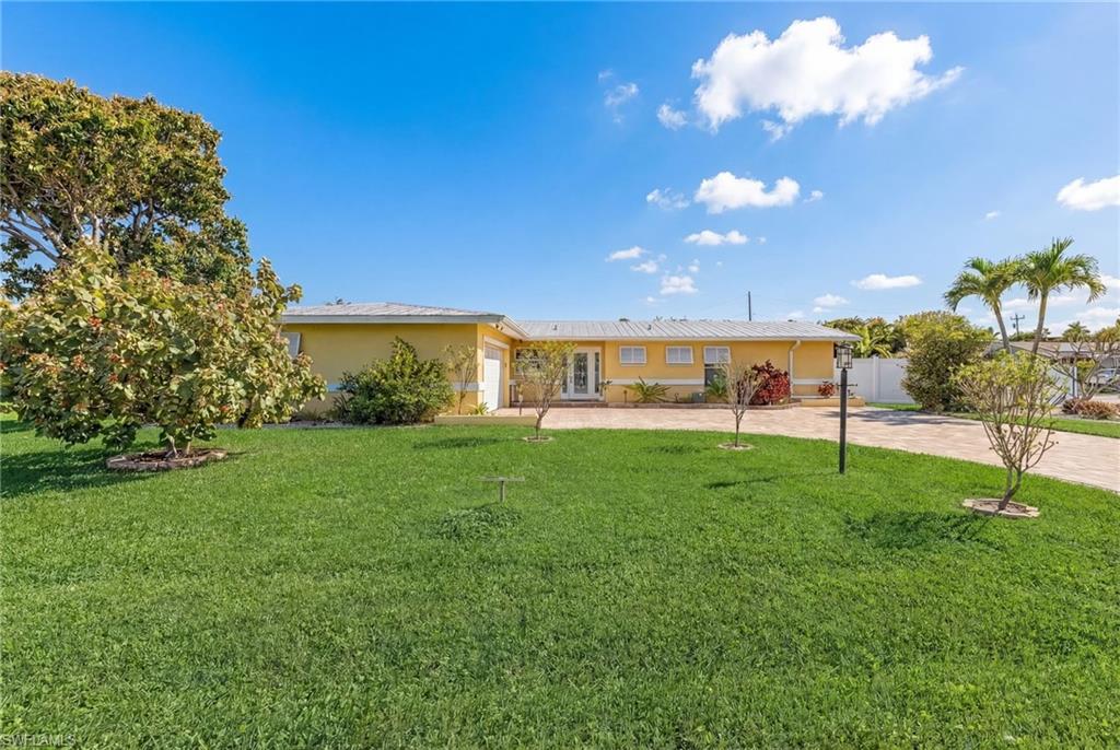 Single story home with stucco siding, a front lawn, a garage, and driveway