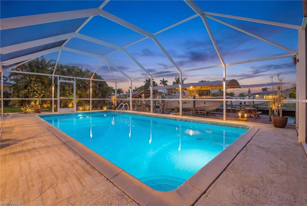 Pool at dusk featuring an outdoor pool, a lanai, and boat lift