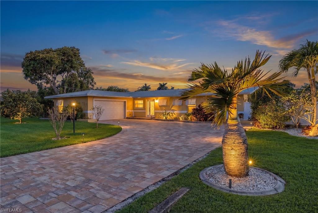 View of front of home with a lawn, driveway, an attached garage, and stucco siding