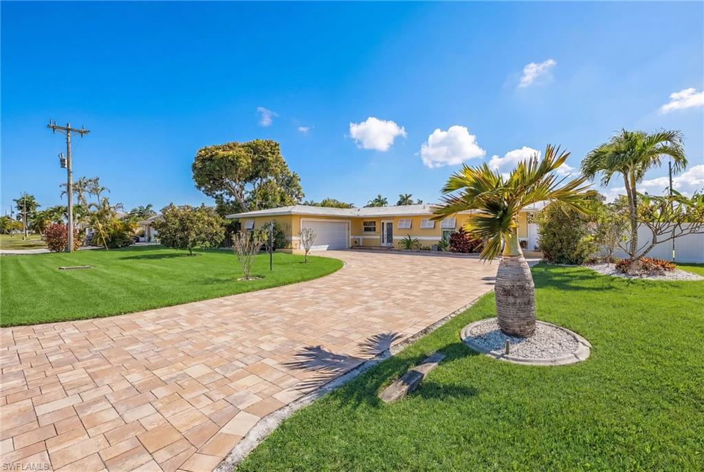 Ranch-style home featuring a front lawn, decorative driveway, and a garage