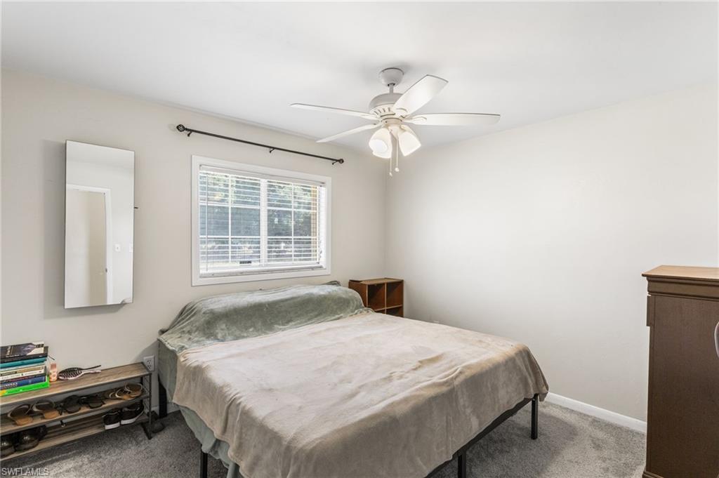 Carpeted bedroom featuring ceiling fan and baseboards