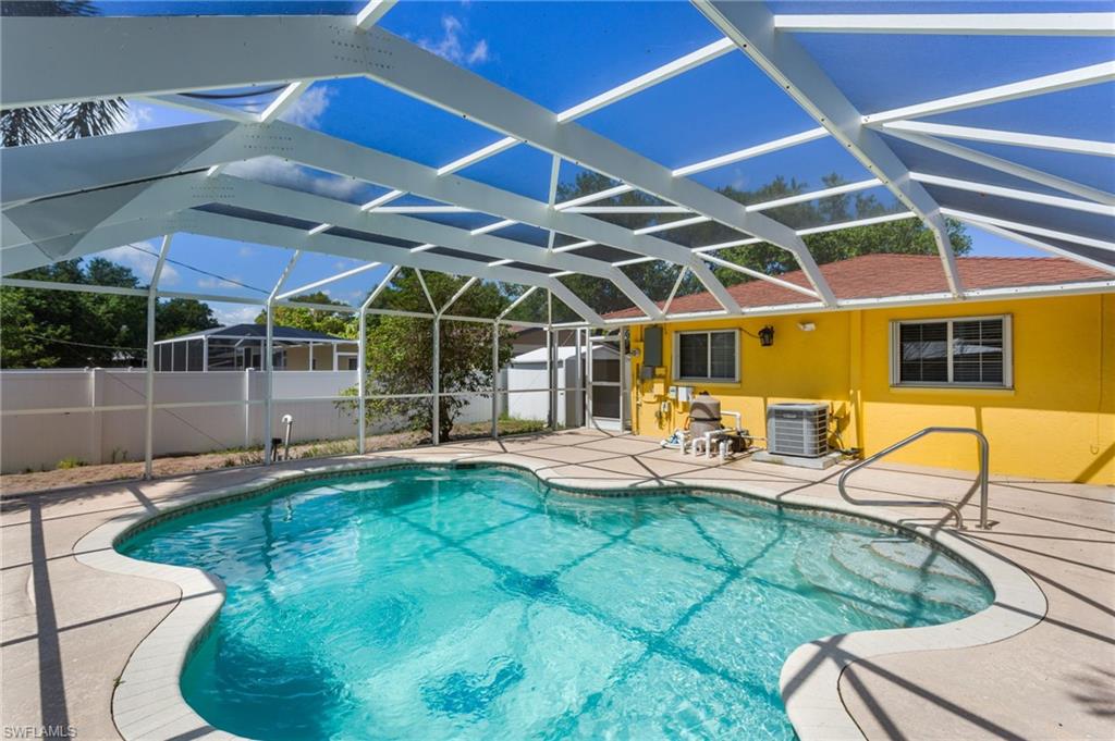 View of swimming pool featuring patio surround, screen enclosure, a sunroom, and a shed!