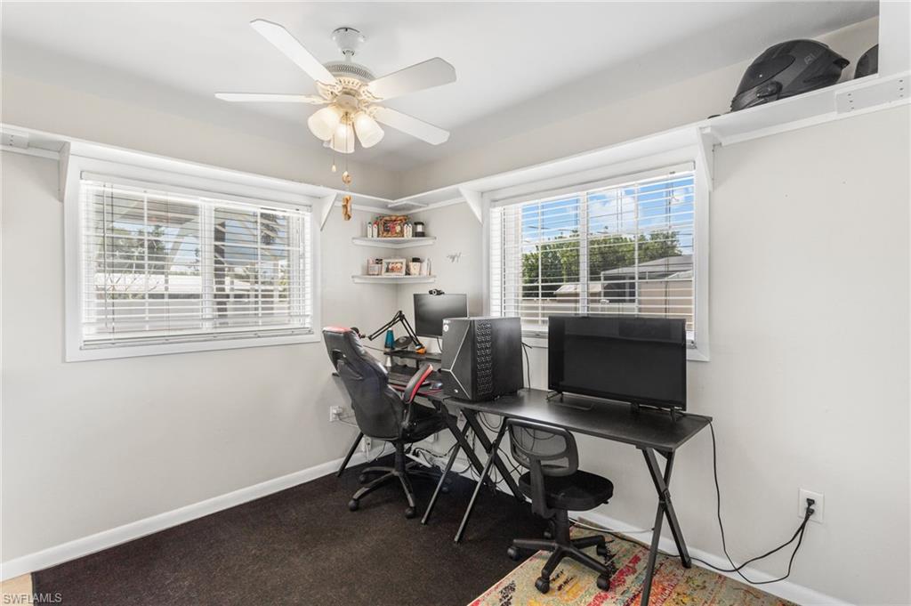 Carpeted home office featuring baseboards and ceiling fan