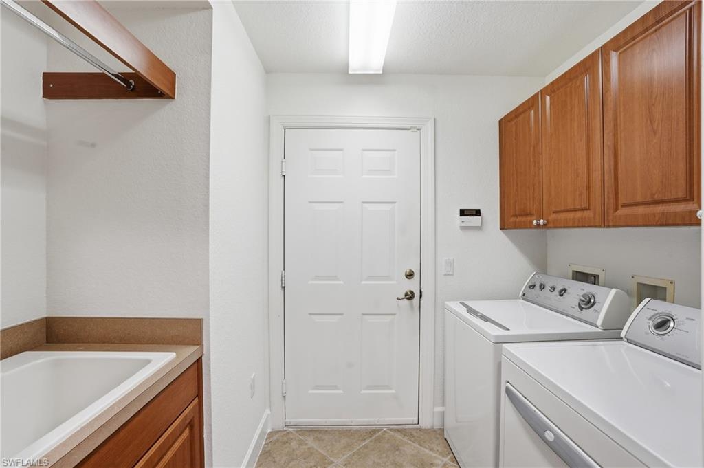 Laundry area featuring cabinet space, separate washer and dryer, light tile patterned floors, and a textured ceiling