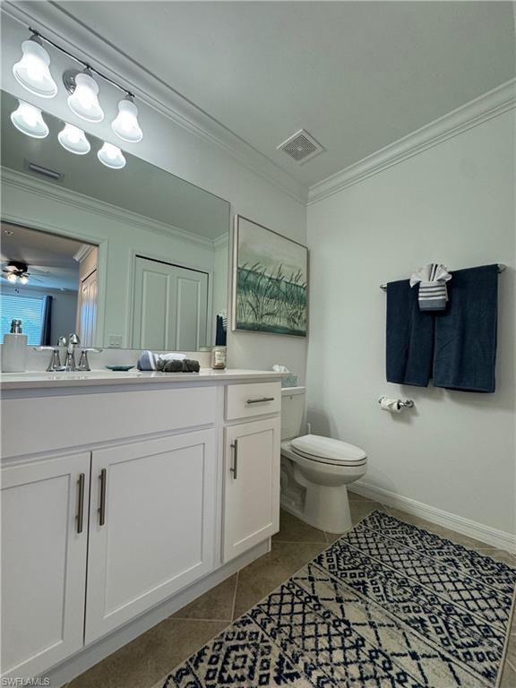 Bathroom featuring vanity, toilet, ornamental molding, and ceiling fan