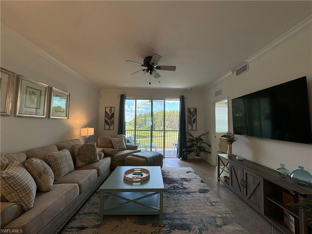 Living room featuring light tile patterned floors, crown molding, and ceiling fan
