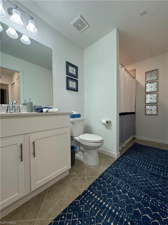 Bathroom featuring vanity, toilet, and tile patterned flooring