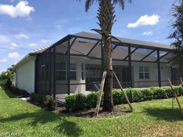 Back of house with enclosure and a yard