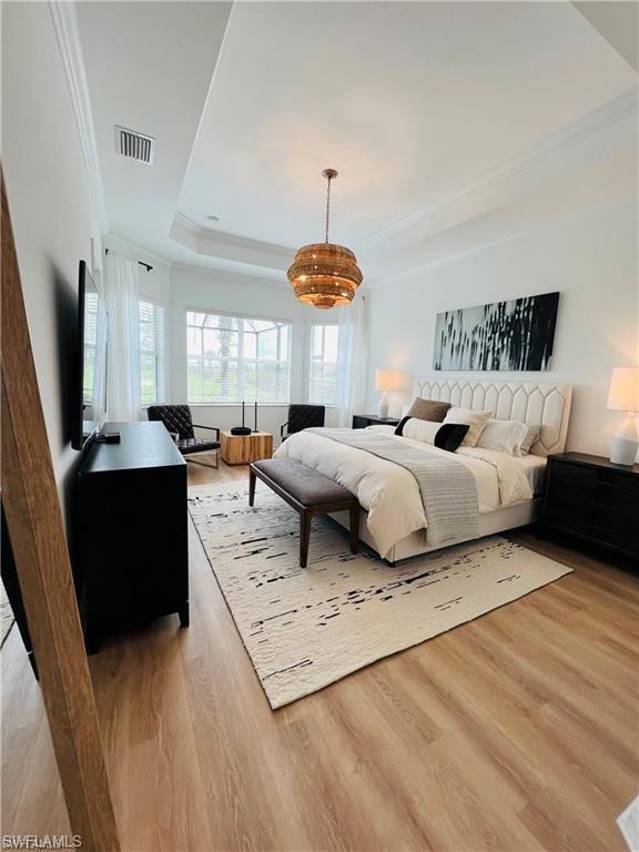Bedroom with crown molding, a raised ceiling, and hardwood / wood-style floors