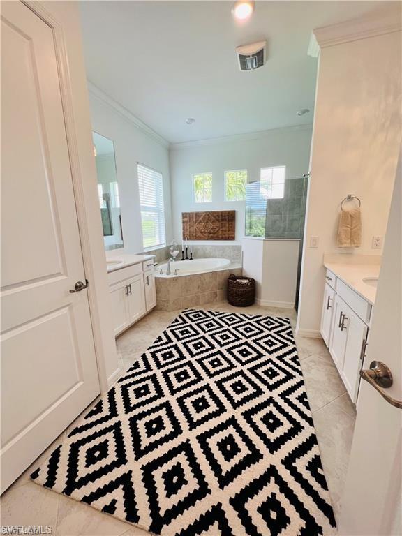 Bathroom featuring tile flooring, tiled tub, and vanity