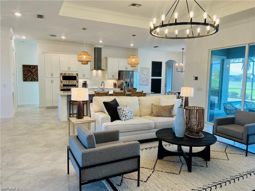 Tiled living room featuring a chandelier, a raised ceiling, and crown molding