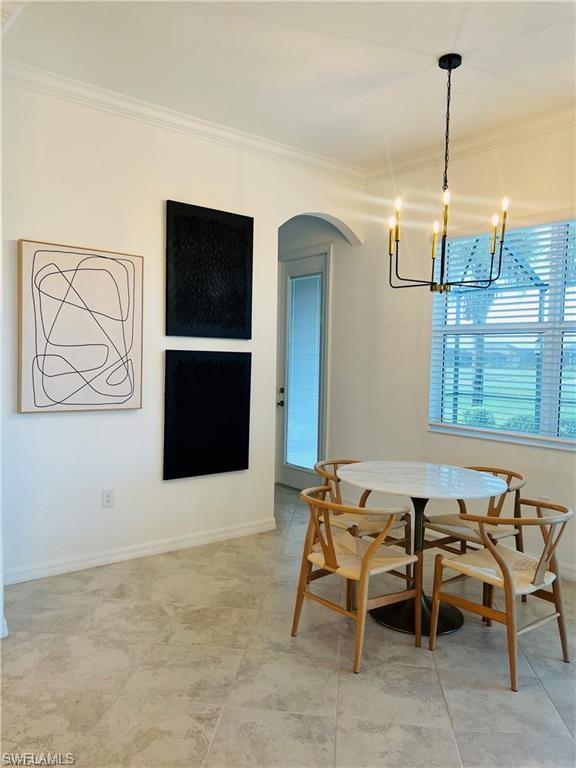 Tiled dining space featuring crown molding and an inviting chandelier