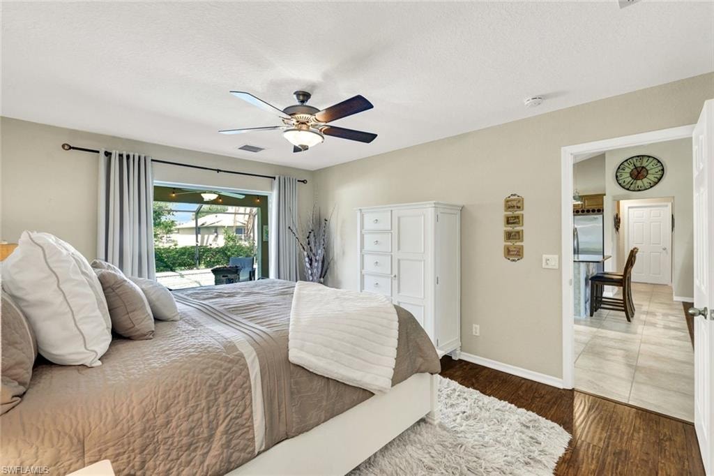 Bedroom featuring a ceiling fan, dark wood-type flooring, access to outside, and freestanding refrigerator