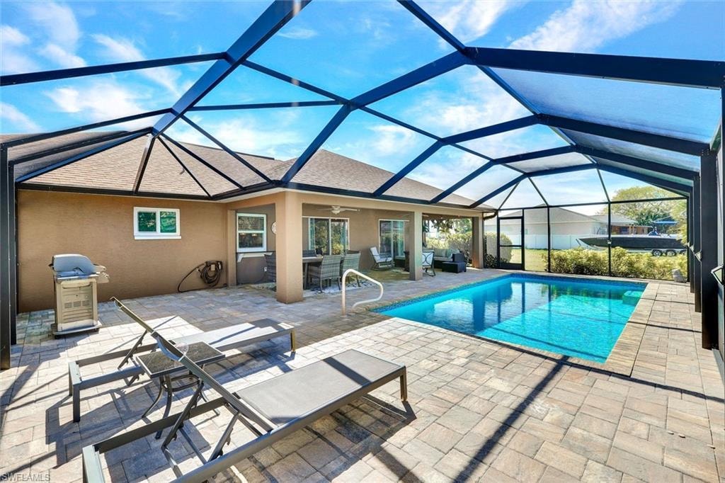 Swimming pool featuring a sunroom, a patio, glass enclosure, grilling area, and outdoor dining space