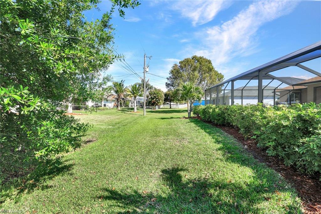 View of grassy yard with a sunroom and glass enclosure