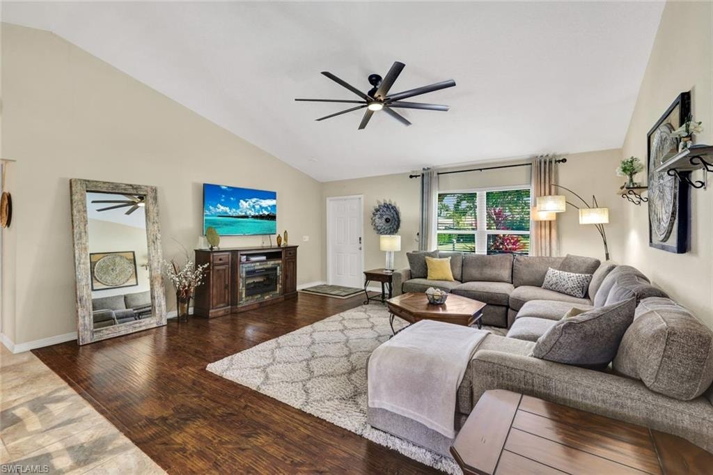 Living room featuring dark wood-style flooring, a ceiling fan, and lofted ceiling