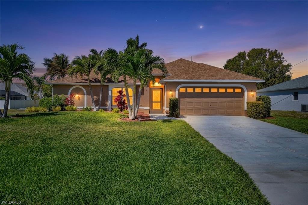 Ranch-style home featuring stucco siding, a garage, a front lawn, concrete driveway, and roof with shingles