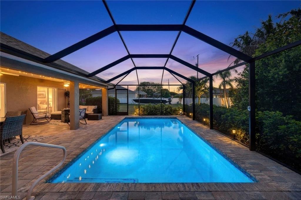 Pool at dusk with an outdoor pool, a sunroom, and glass enclosure