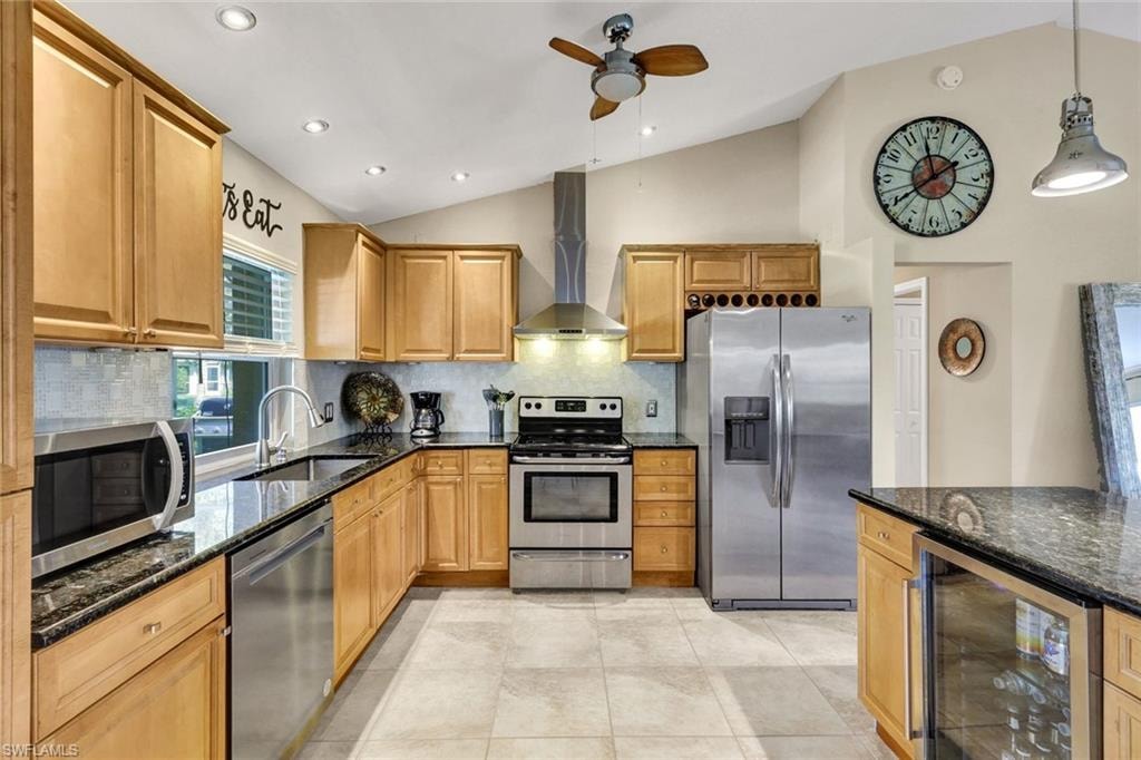 Kitchen featuring decorative backsplash, stainless steel appliances, wine cooler, dark stone counters, and lofted ceiling
