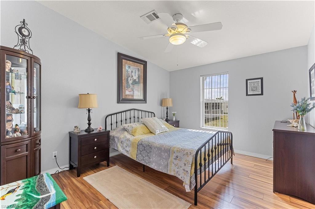 Bedroom with light wood-style floors, ceiling fan, and lofted ceiling