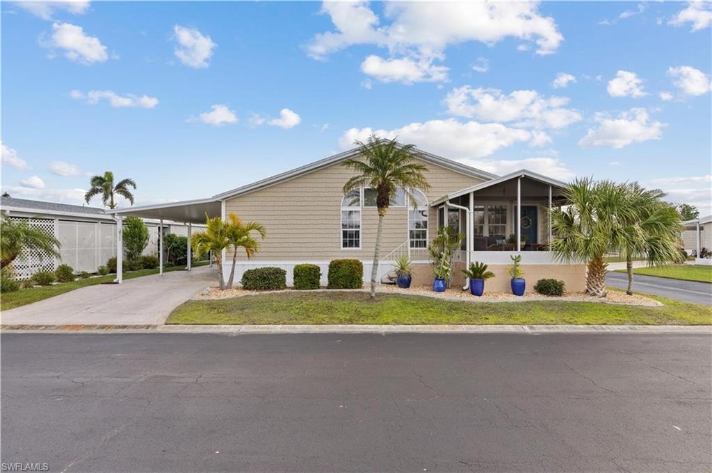 Manufactured / mobile home with an attached carport, a sunroom, driveway, and a front yard