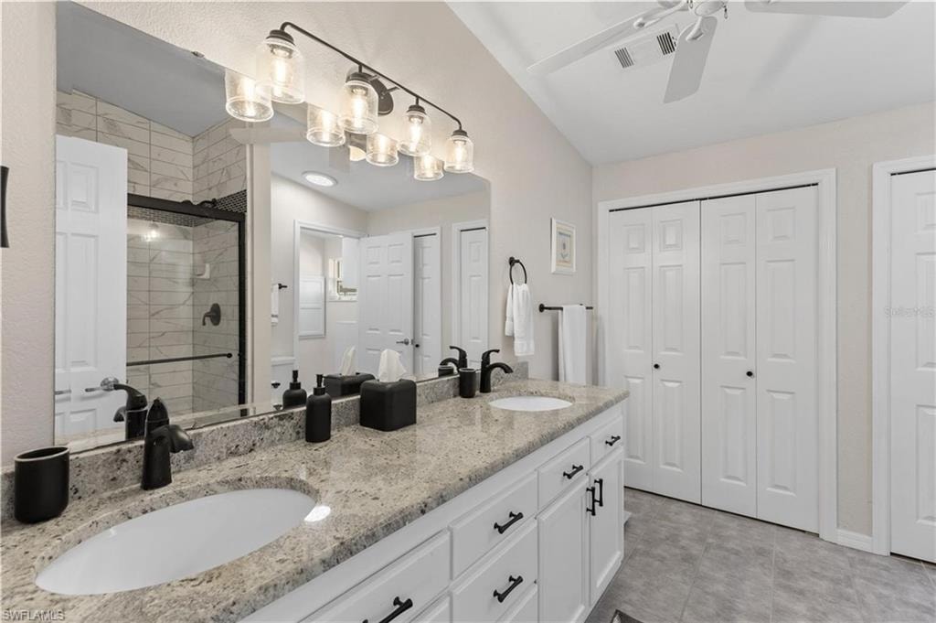 Full bathroom featuring a closet, double vanity, a shower stall, and ceiling fan