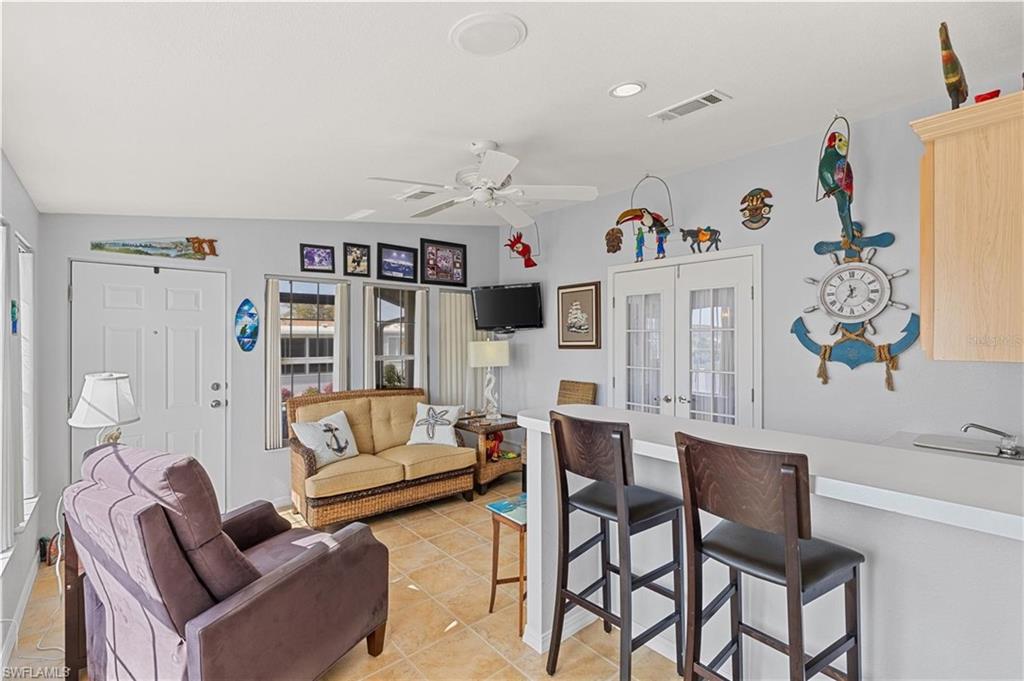 Living area with a ceiling fan, light tile patterned floors, french doors, and recessed lighting