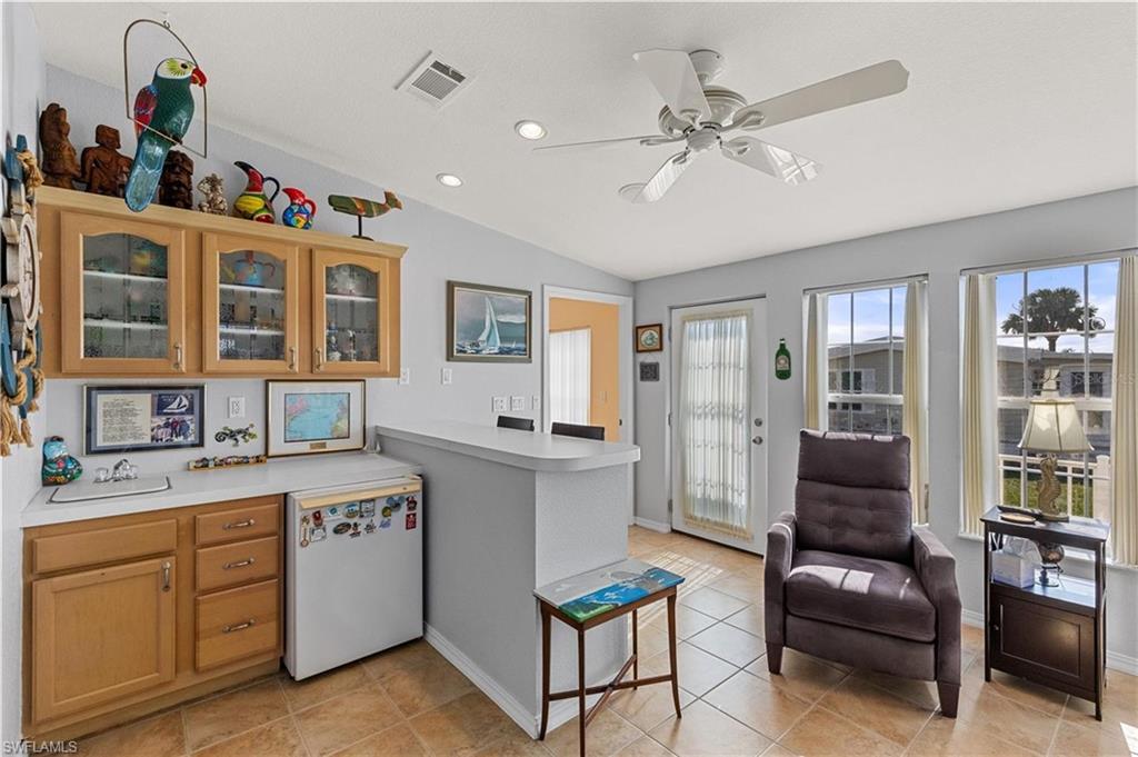 Kitchen with light countertops, glass fronted cabinets, white fridge, ceiling fan, and a peninsula
