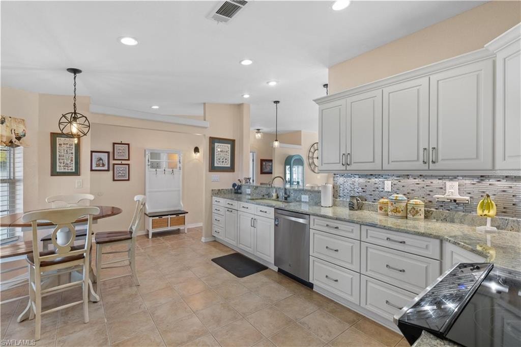 Kitchen featuring light stone counters, stainless steel dishwasher, black range with electric cooktop, tasteful backsplash, and decorative light fixtures
