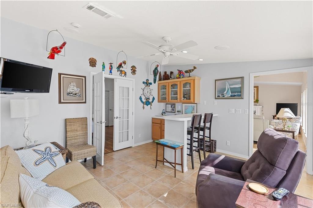 Living area with a ceiling fan, light tile patterned floors, and french doors