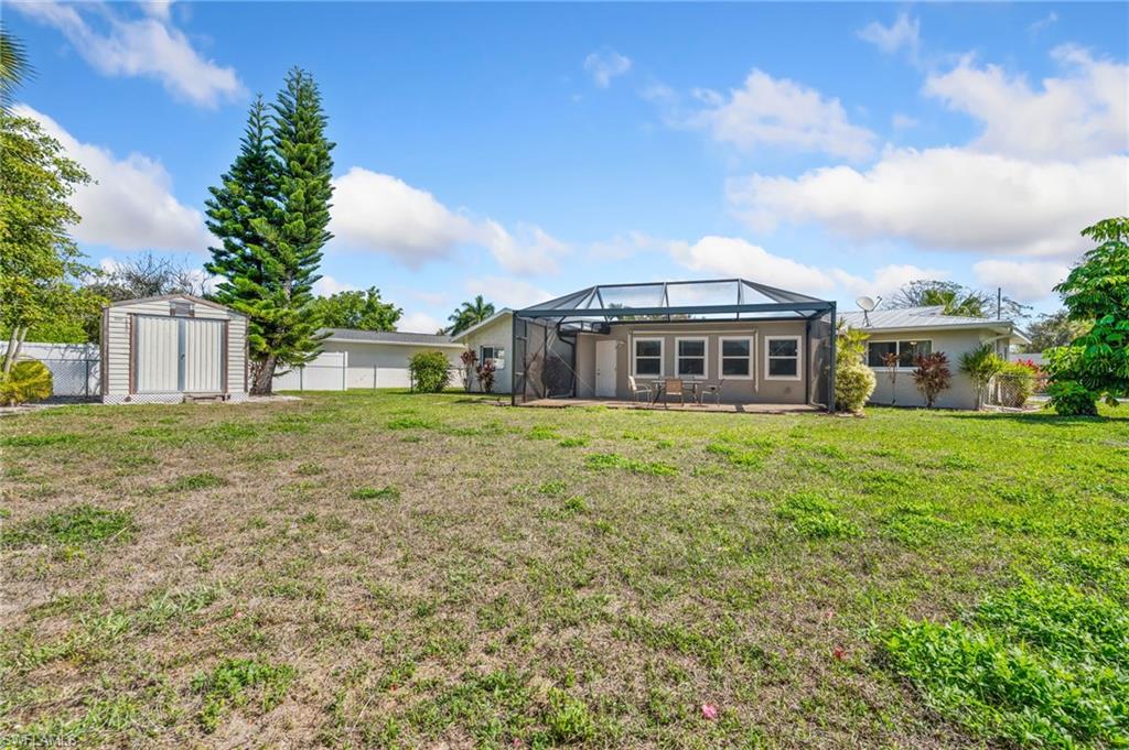 Back of property featuring a patio area, a shed, a fenced backyard, a lanai, and a sunroom