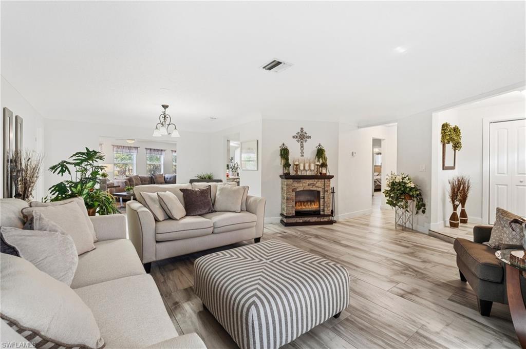 Living room with wood finished floors, a fireplace, and a chandelier