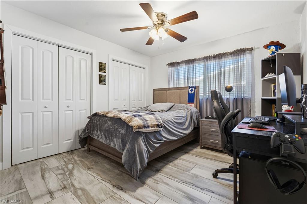 Bedroom featuring a desk, two closets, ceiling fan, and light wood-style floors