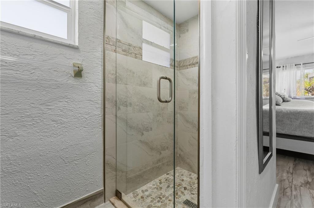 Full bathroom featuring plenty of natural light, connected bathroom, a marble finish shower, and a textured wall