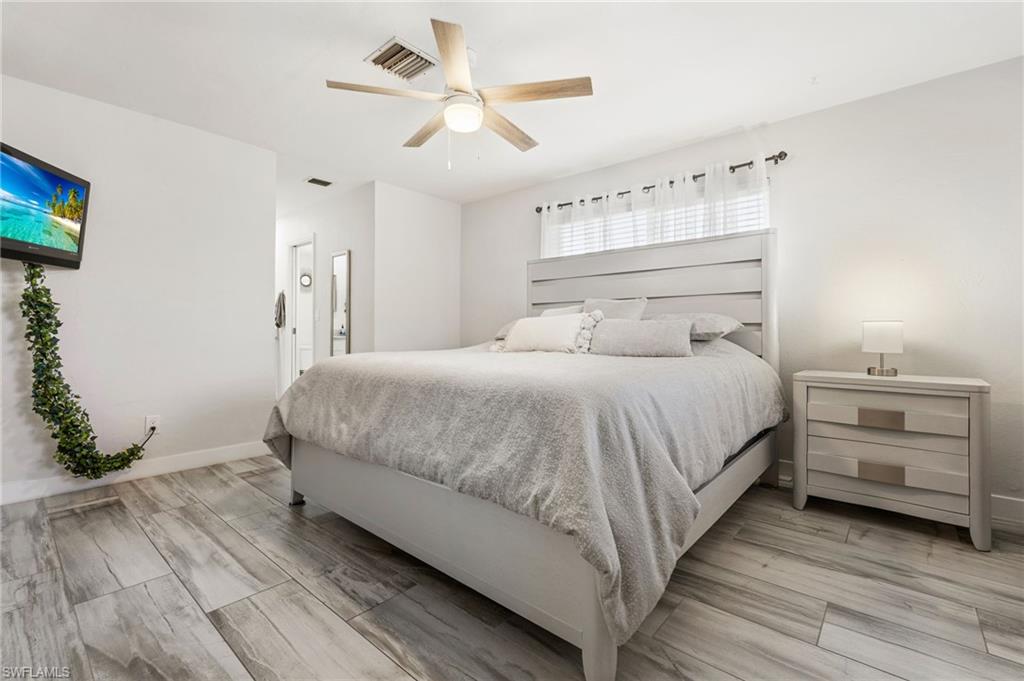Bedroom with wood tiled floors, a ceiling fan, and ensuite bathroom