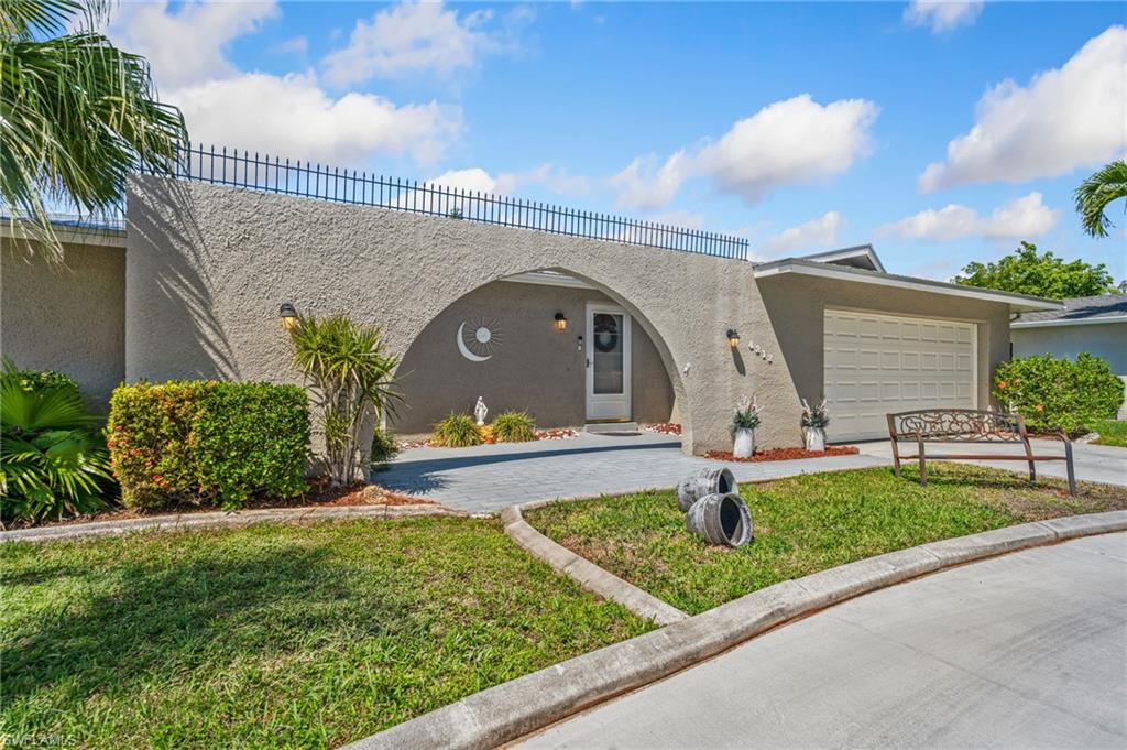 View of front of house with stucco siding, driveway, an attached garage, and a front yard