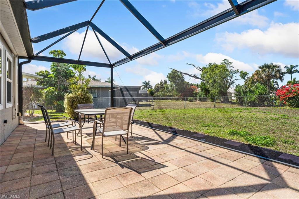 Fenced backyard featuring a patio area, outdoor dining space, a sunroom, and glass enclosure