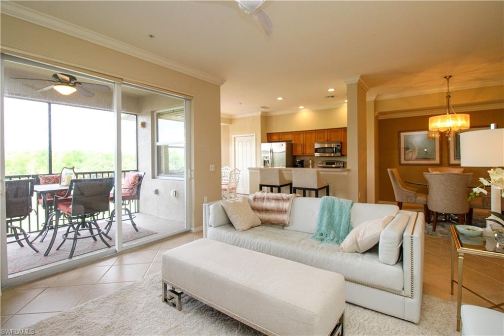 Living room with crown molding, recessed lighting, light tile patterned floors, and ceiling fan with notable chandelier