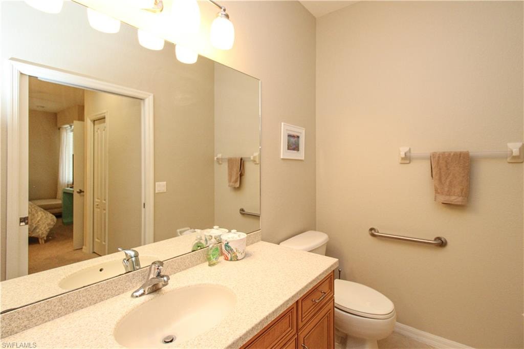 Bathroom featuring toilet, vanity, and baseboards