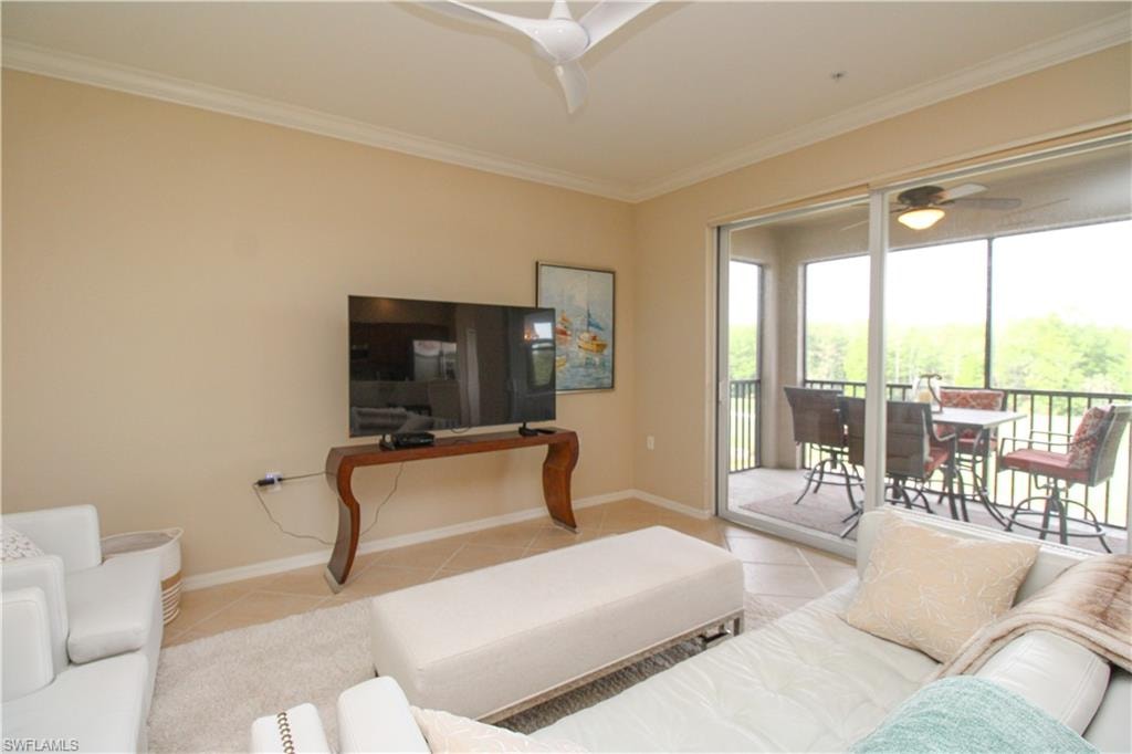 Living room with baseboards, crown molding, tile patterned flooring, and a ceiling fan
