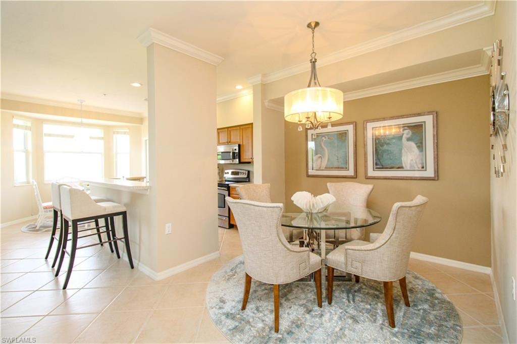 Dining space with baseboards, a chandelier, ornamental molding, and light tile patterned floors
