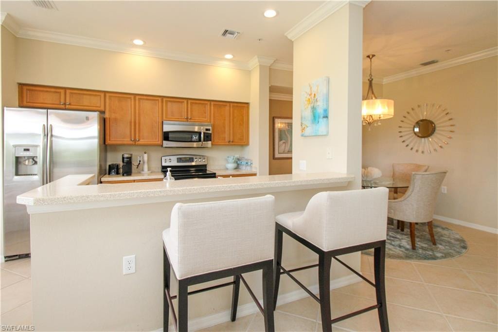 Kitchen featuring light tile patterned flooring, visible vents, brown cabinetry, and stainless steel appliances